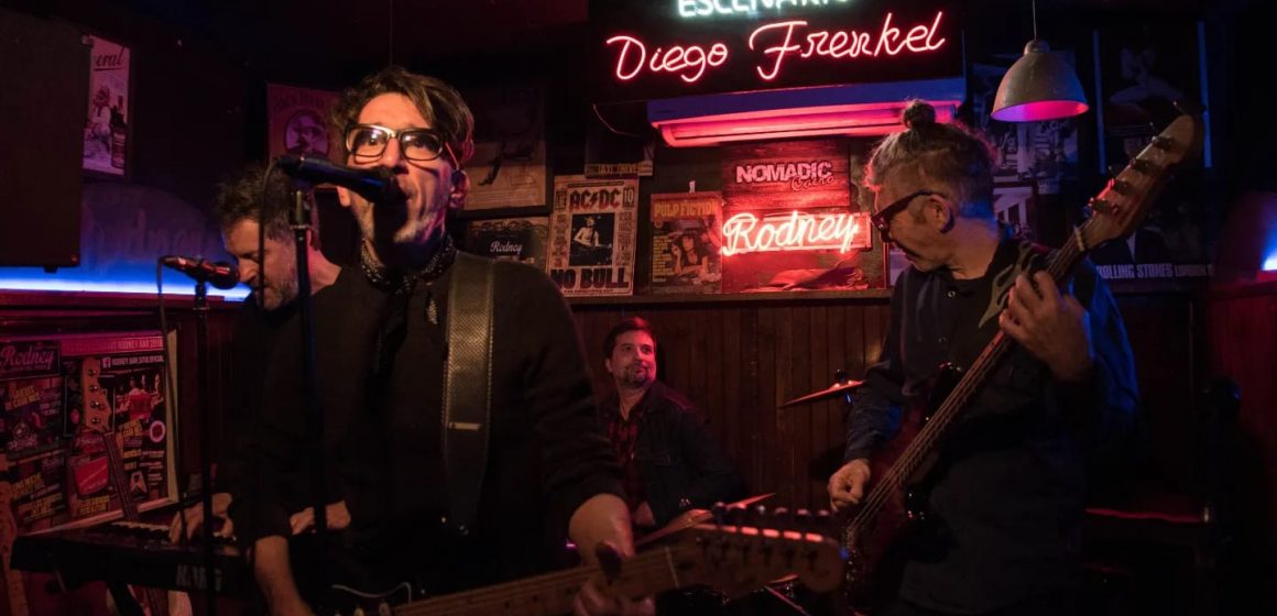 El Rodney bar de Chacarita cumplió cuatro décadas y homenajeó a Diego Frenkel y a La Portuaria bautizando escenario y living con sus nombres: “La verdad, no sabía que me iba a emocionar tanto ante los neones, los nombres nuestros puestos ahí y un público fervoroso”, revela el cantautor ante lo acontecido